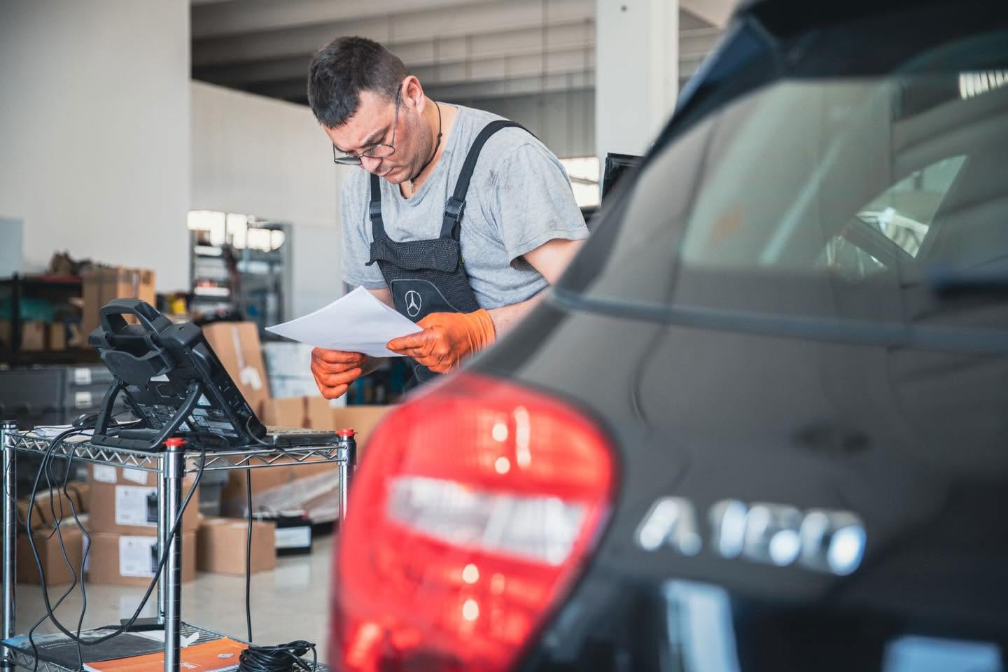 Tecnico al lavoro sul vano motore durante un tagliando